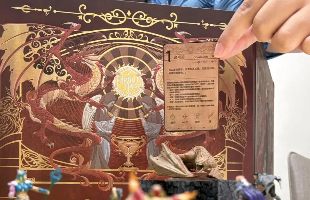 手把一張法術卡夾在金紅色的 GM 屏風上